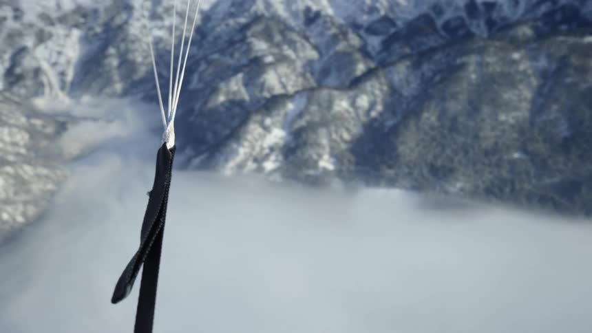 A person parachuting above many mountains and fog