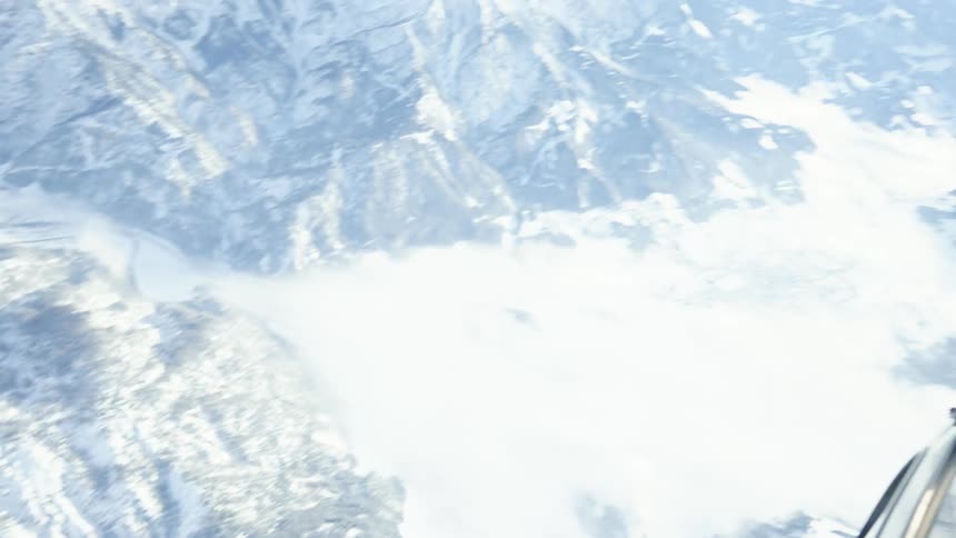 A helicopter flies over a snow covered mountain range