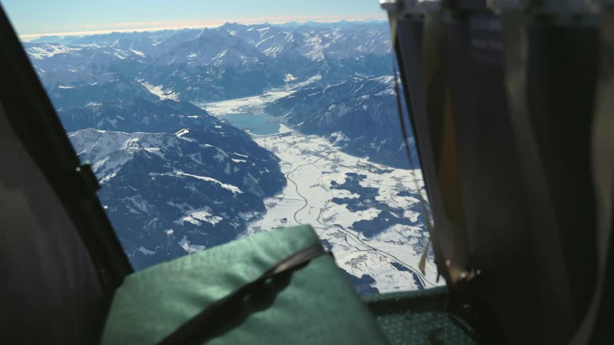 Two parachuters jumping from a helicopter over snowy mountains