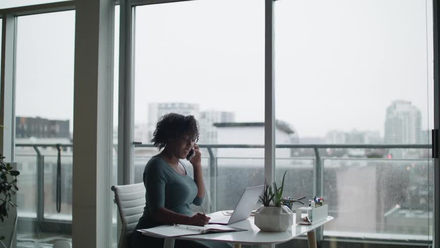 A woman talks on her cell phone at her desk