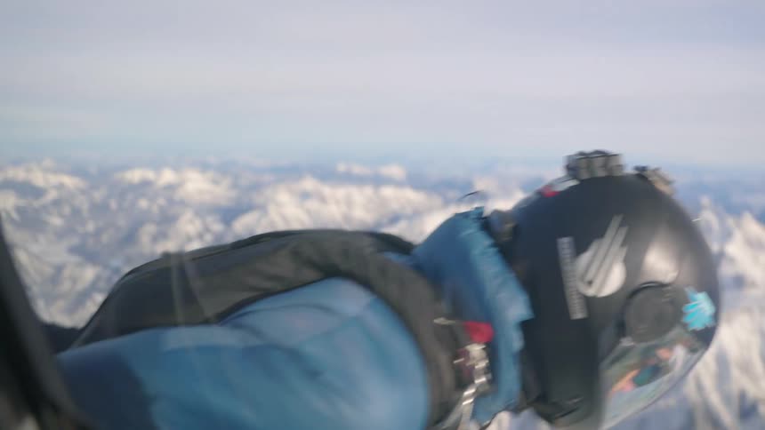 A man with a helmet skydiving from a helicopter with the sky and clouds in the background