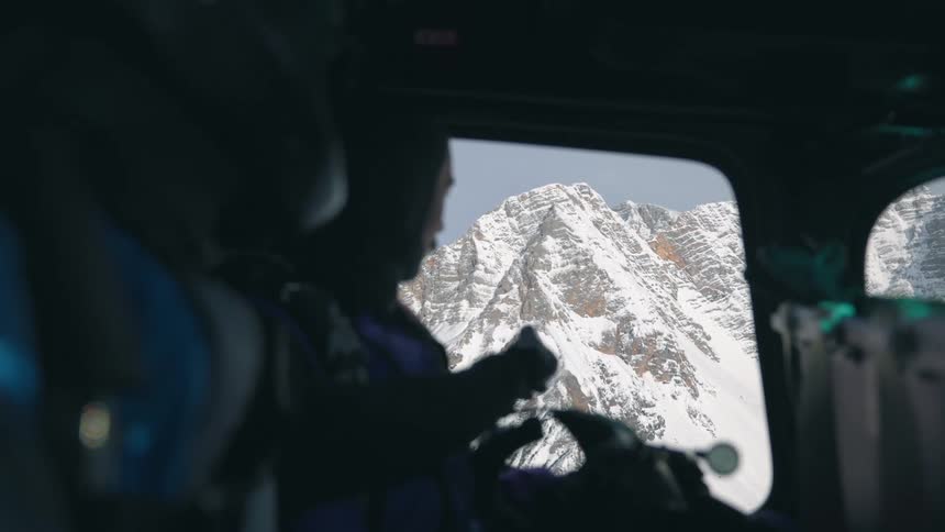 People flying in a helicopter over a mountain range looking out