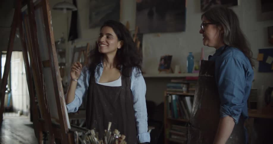 Two artists talking in front of a canvas in an art studio