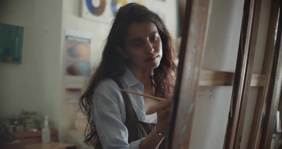 A woman painting on a canvas in a studio