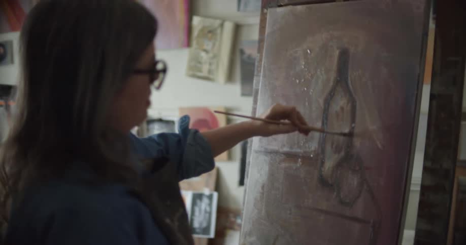 A woman painting on a canvas in a studio