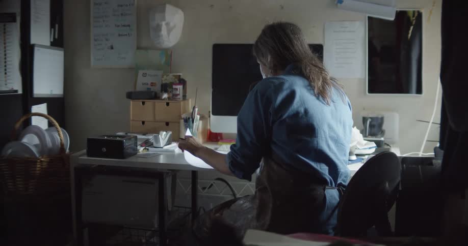 A person sits at a small desk writing on papers