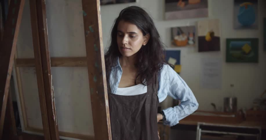 Woman in front of canvas contemplating what to paint in an art studio