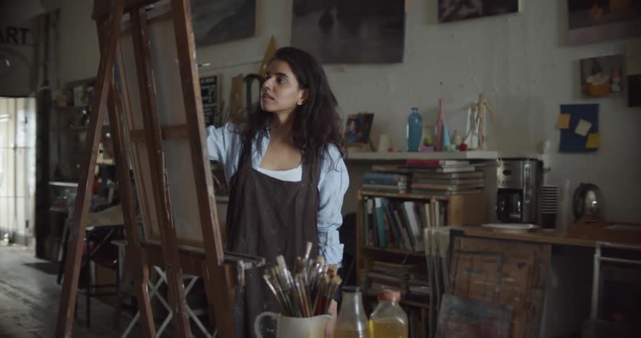 A female artist painting on a canvas in an art studio
