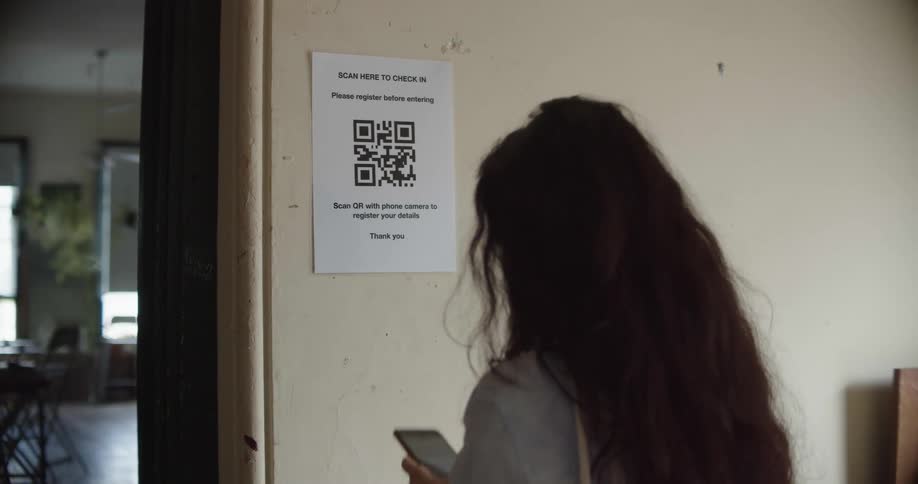 A woman with a smart phone scanning a qr code and walking through a doorway