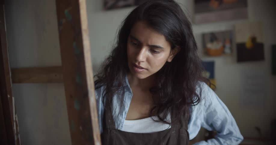 A woman painting steps back and looks at her artwork