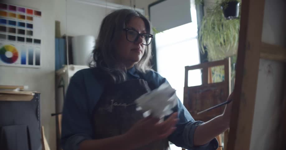 A woman is painting in her studio