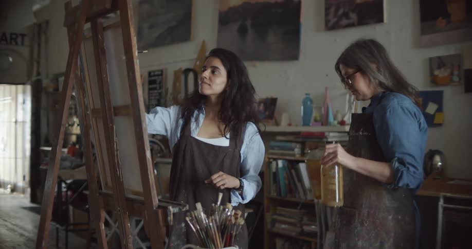 A woman carries two bottles away from the painter