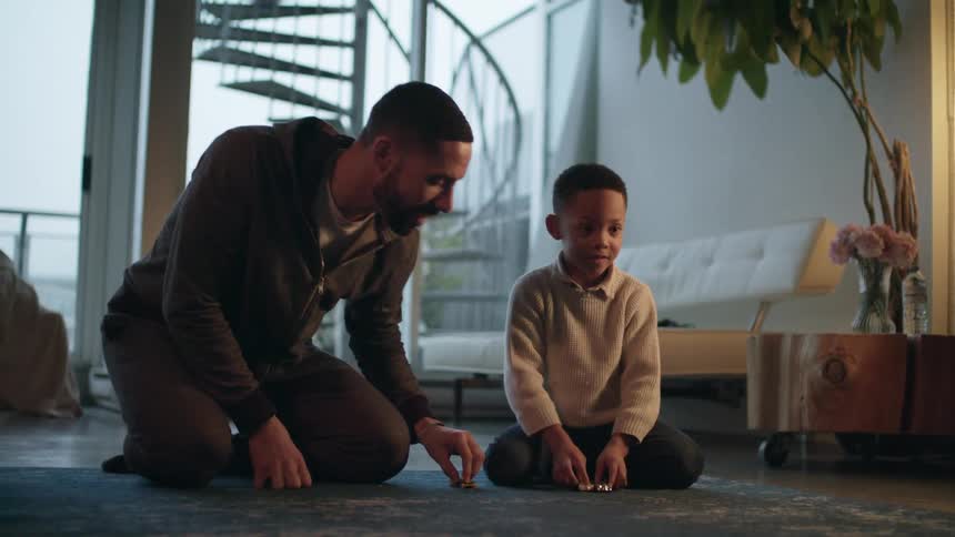 A father and son playing with toy cars in a house