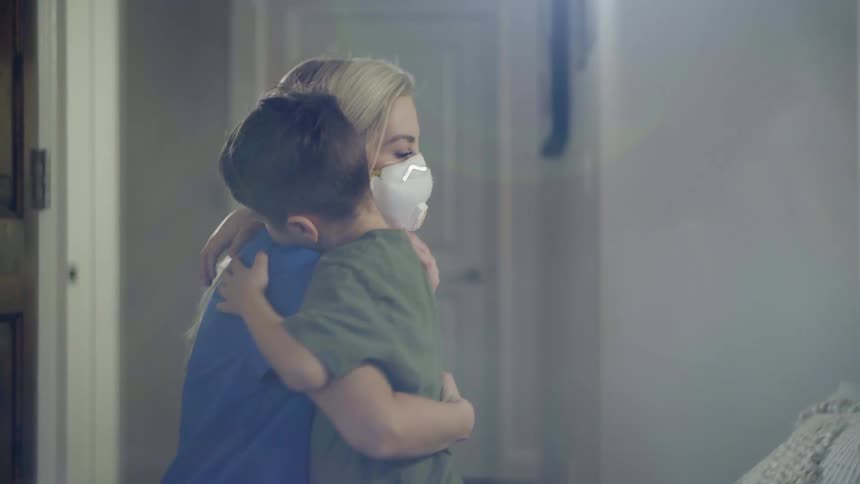A woman hugs a child in the hallway