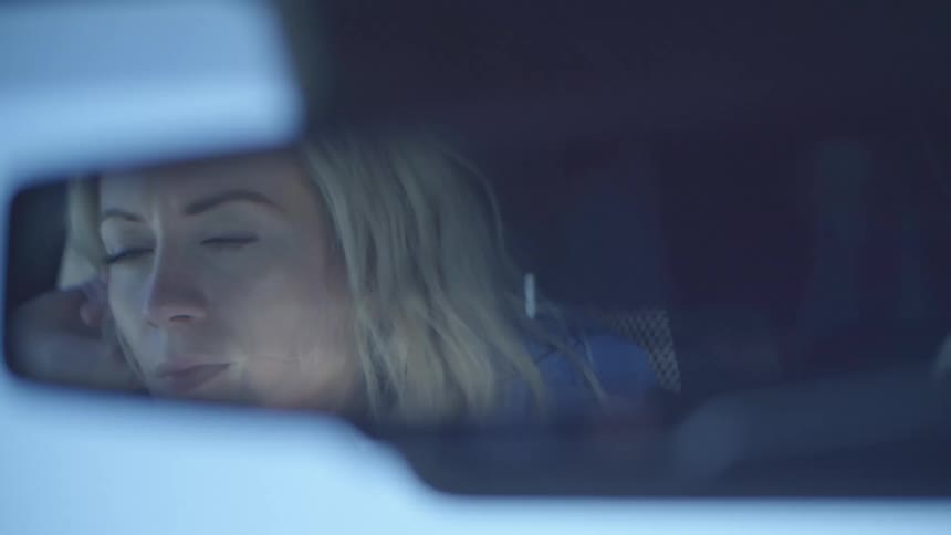 A woman is driving a car at dusk