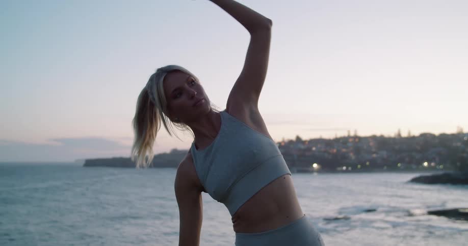 A woman stretching near the ocean