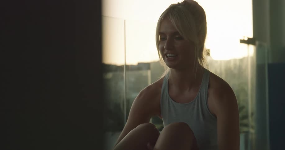 A woman performing a simple exercise movement on a balcony at sunrise