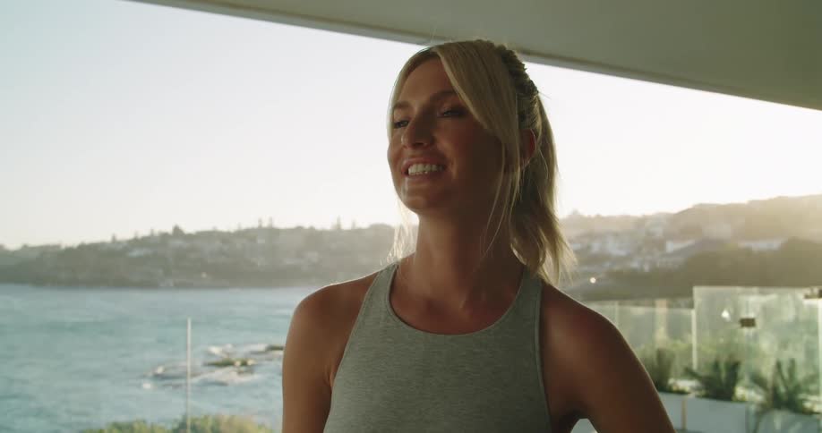 A woman in a sports bra smiling and posing with an exercise ball