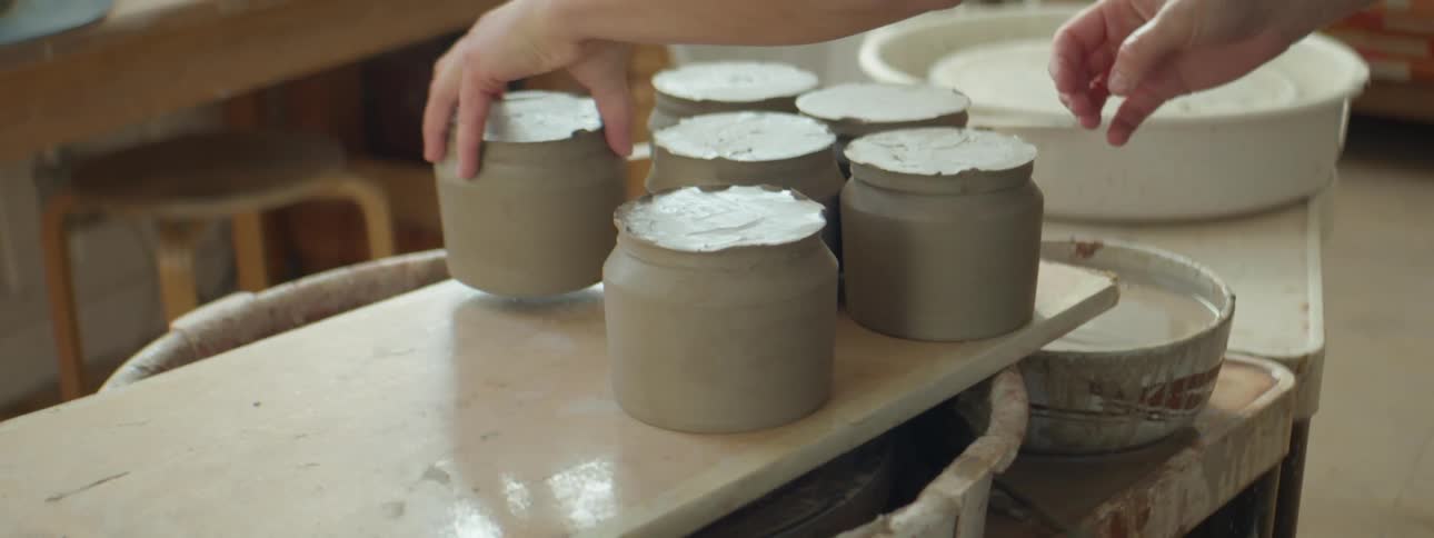 A person is moving clay cups on a table