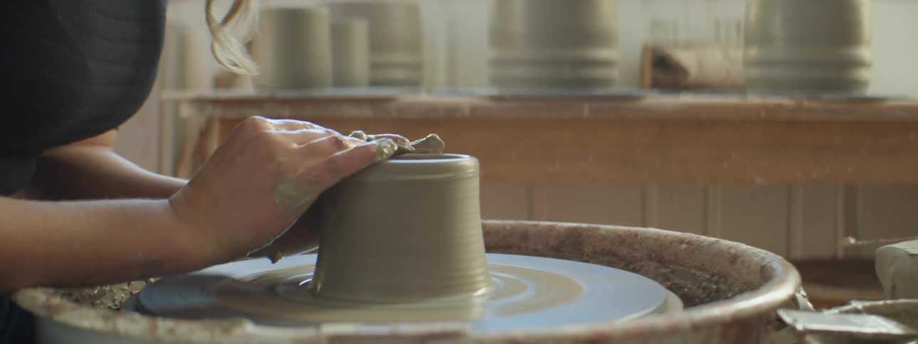 A person shaping clay on a pottery wheel