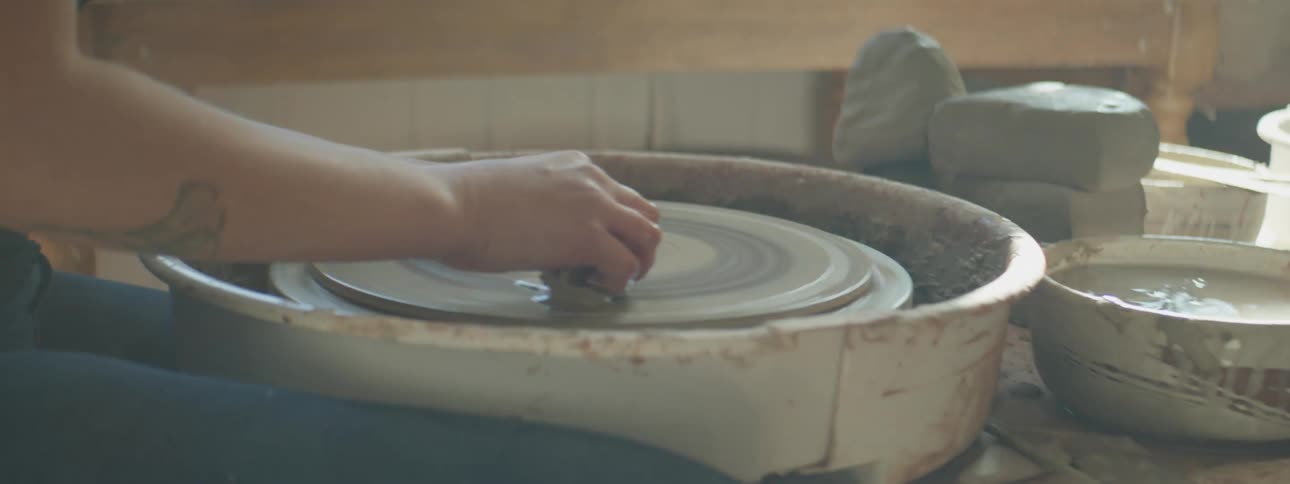 A person is sitting in a room and making pottery