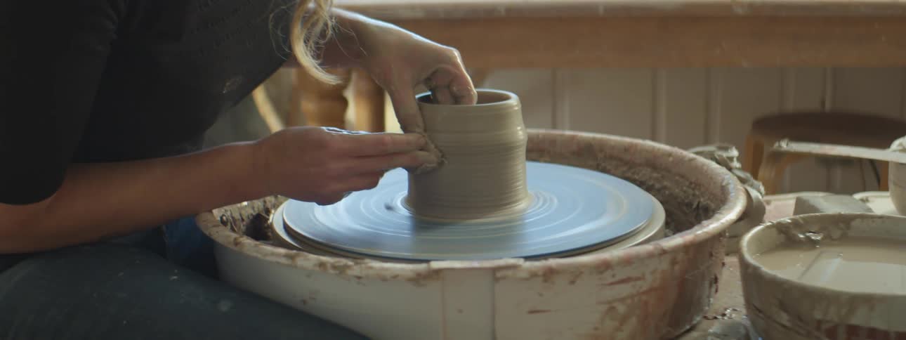 A sculptor working on a vase on a wheel