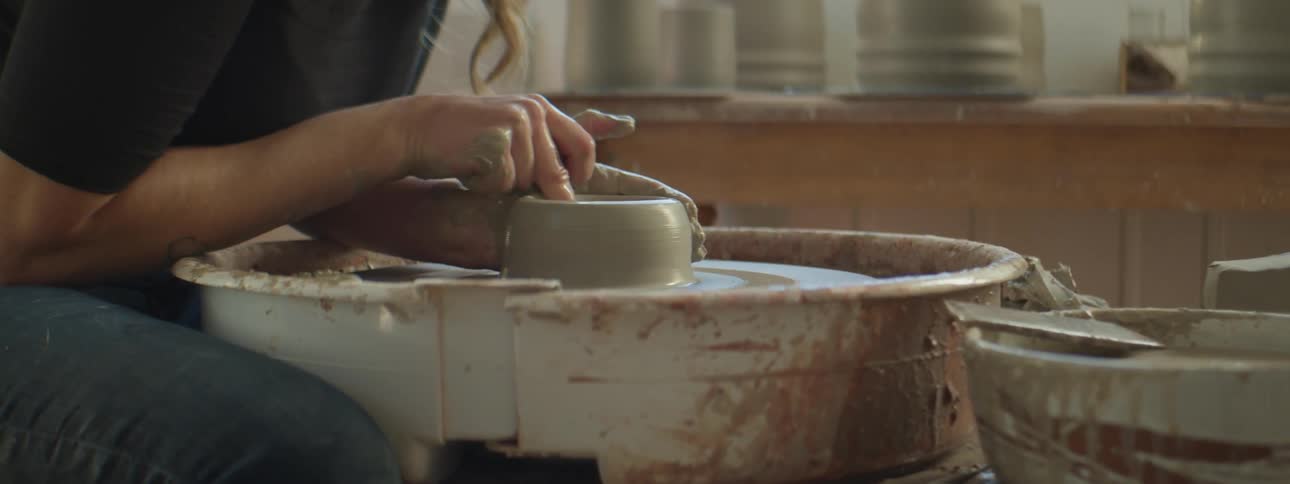 Woman sculpting clay on pottery wheel in an art studio