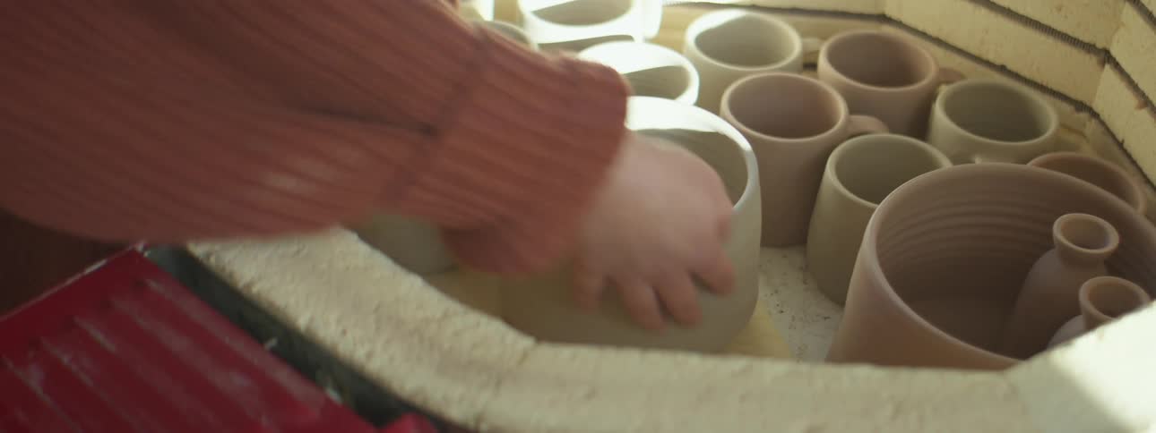 A woman puts pottery in to a kiln