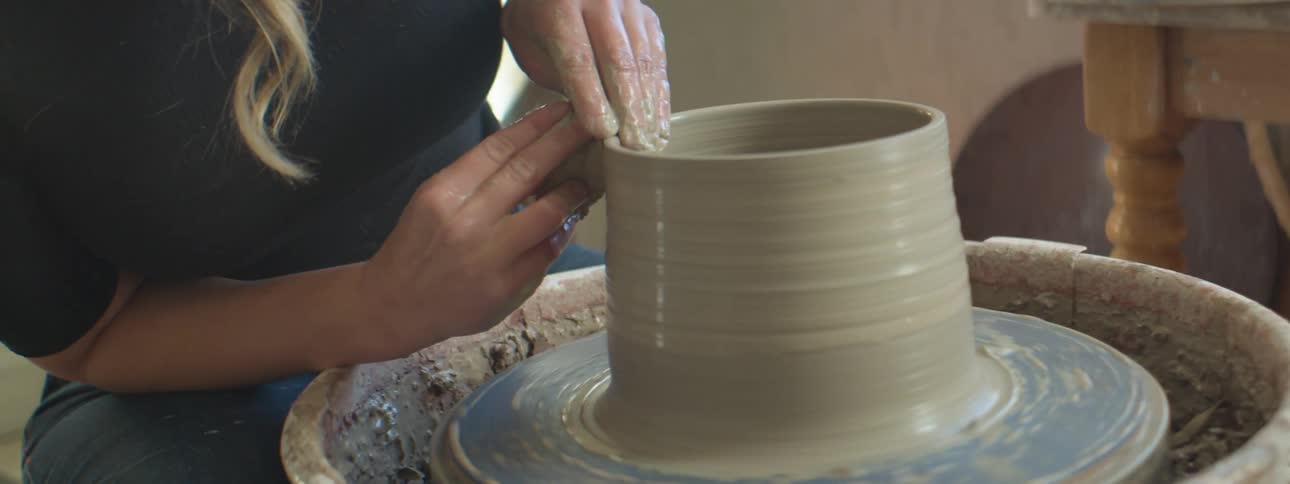 A woman is making pottery indoors during the day