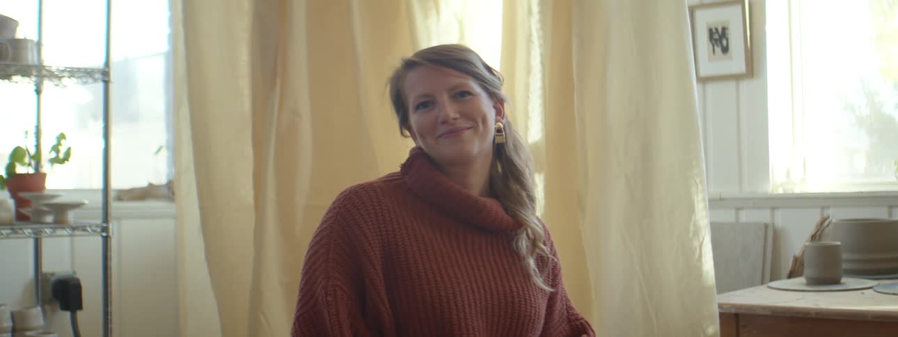 A woman smiles into the camera while sitting indoors during the day