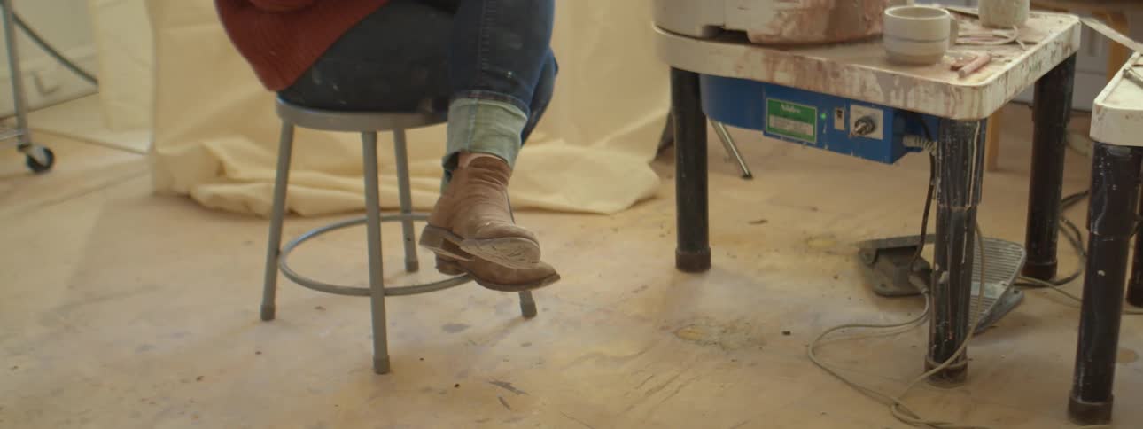 A woman sits by a table that she was doing ceramics at