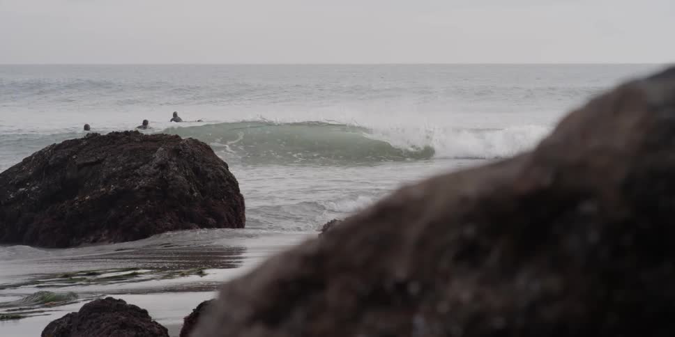 People are surfing near the shore on a cloudy day