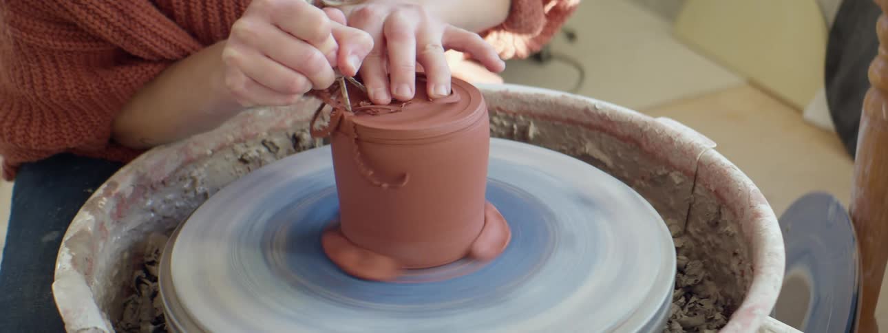 A woman shaping clay on a rotating pottery wheel