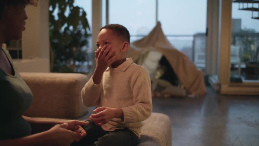 A boy plays a clapping game with his mother on the couch