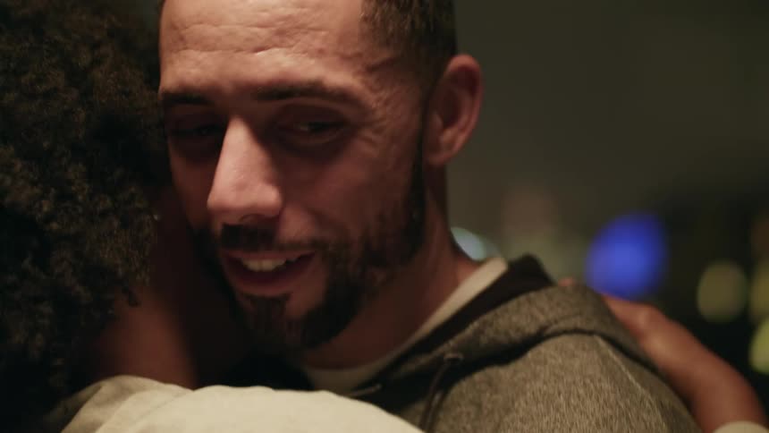 A man hugging his girlfriend and smiles while talking to her