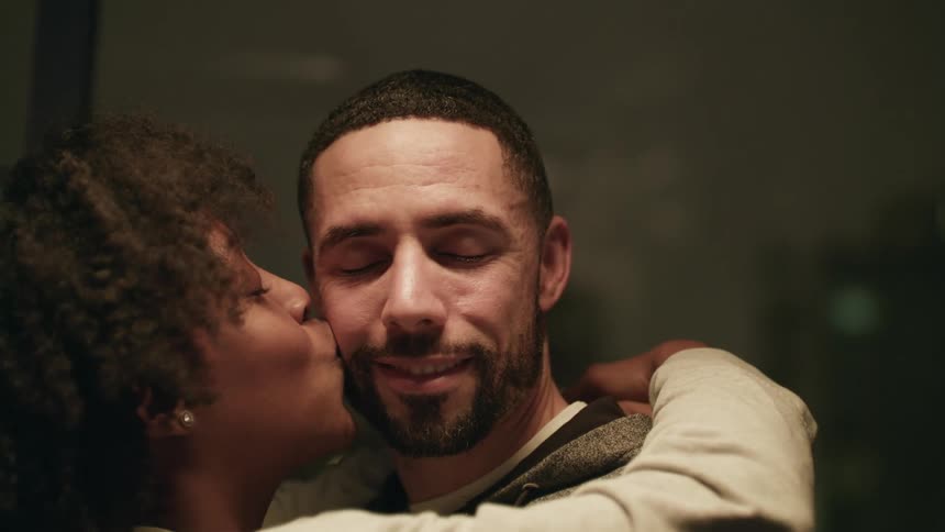 A man and a woman dancing and hugging while the woman kiss the man on his cheek