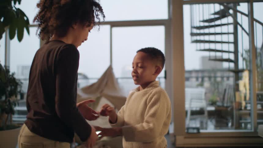 A young brother and sister playing in front of a window