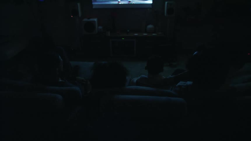 A family sits on a couch at night and watches television