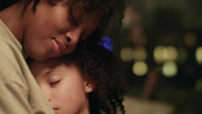 A mother hugging her daughter that is asleep