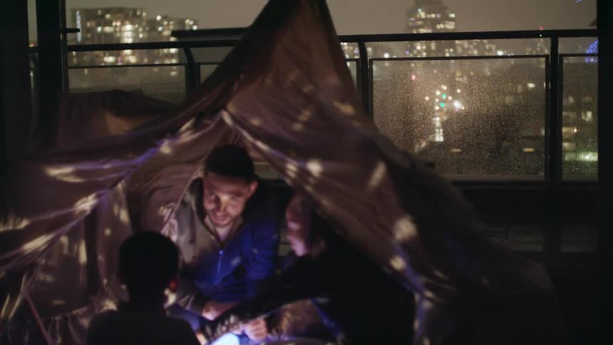 A man a boy and a girl in a tent in a room with windows in the background