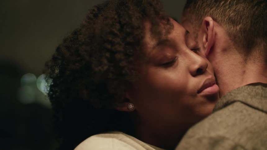 A woman smiles as she hugs a man