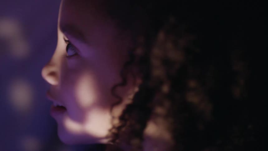 A little girl in a room with lights shining on her face