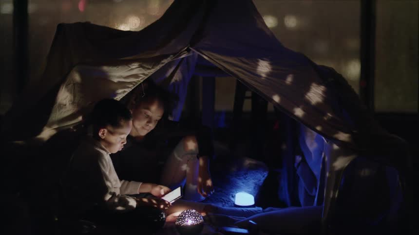 A boy and a girl in a room in a tent looking at a tablet