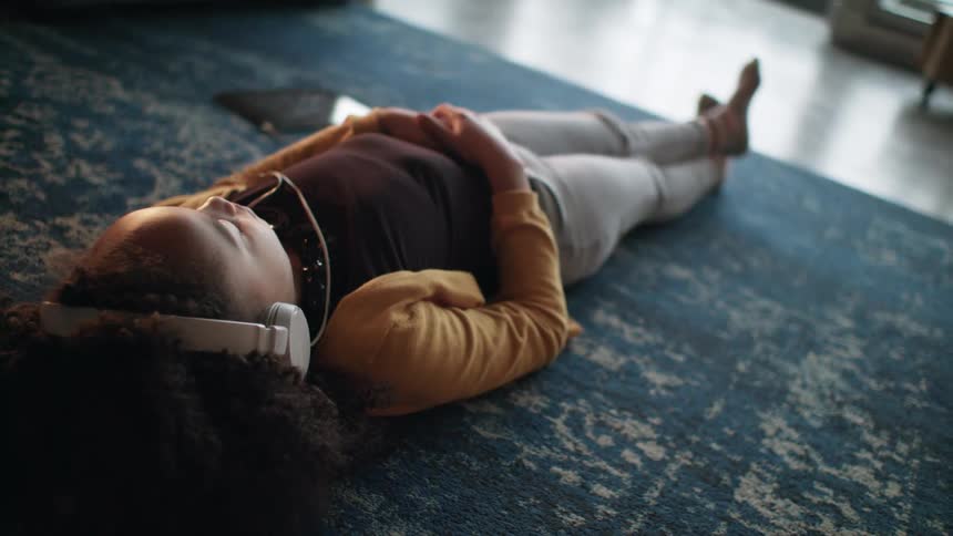 A young woman laying on the floor listening to tablet with headphones