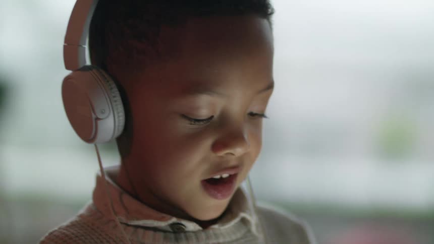 Young boy wearing headphones listening to music in the living room at home