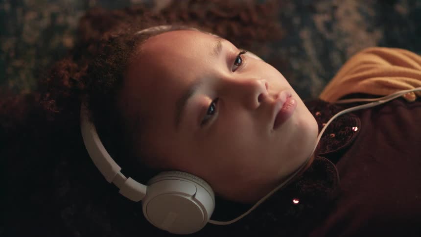 A girl laying on the floor on a carpet with headphones