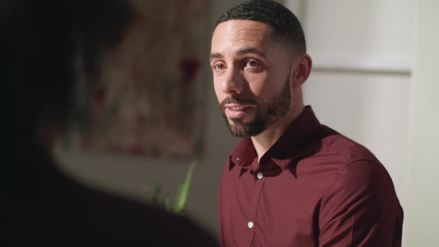 A man smiling while talking to a woman indoors