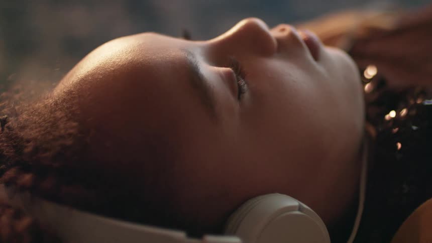 A young girl listening to headphones while lying down