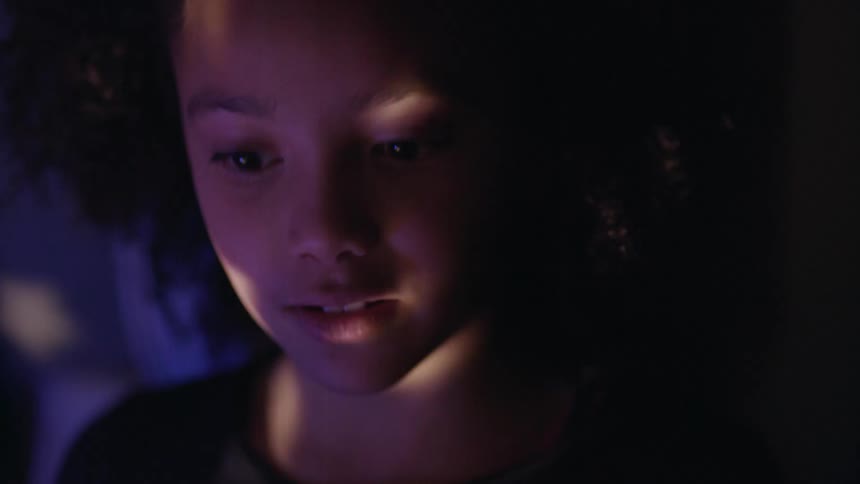 A young girl talks as star lights are projected on and pass over her face