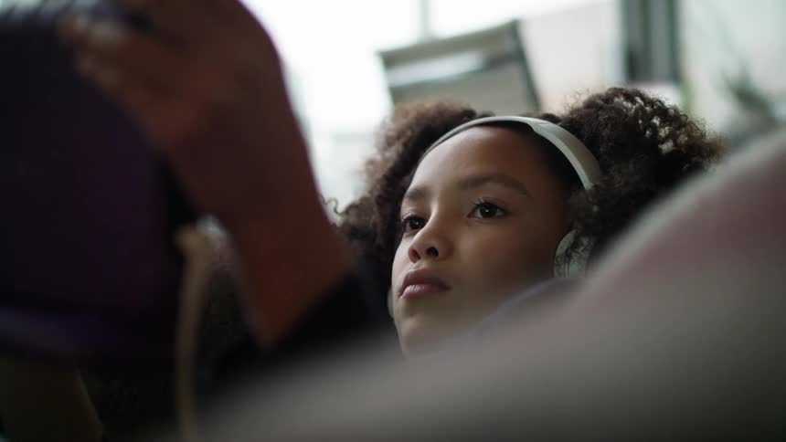A child sitting in a chair relaxing with headphones on